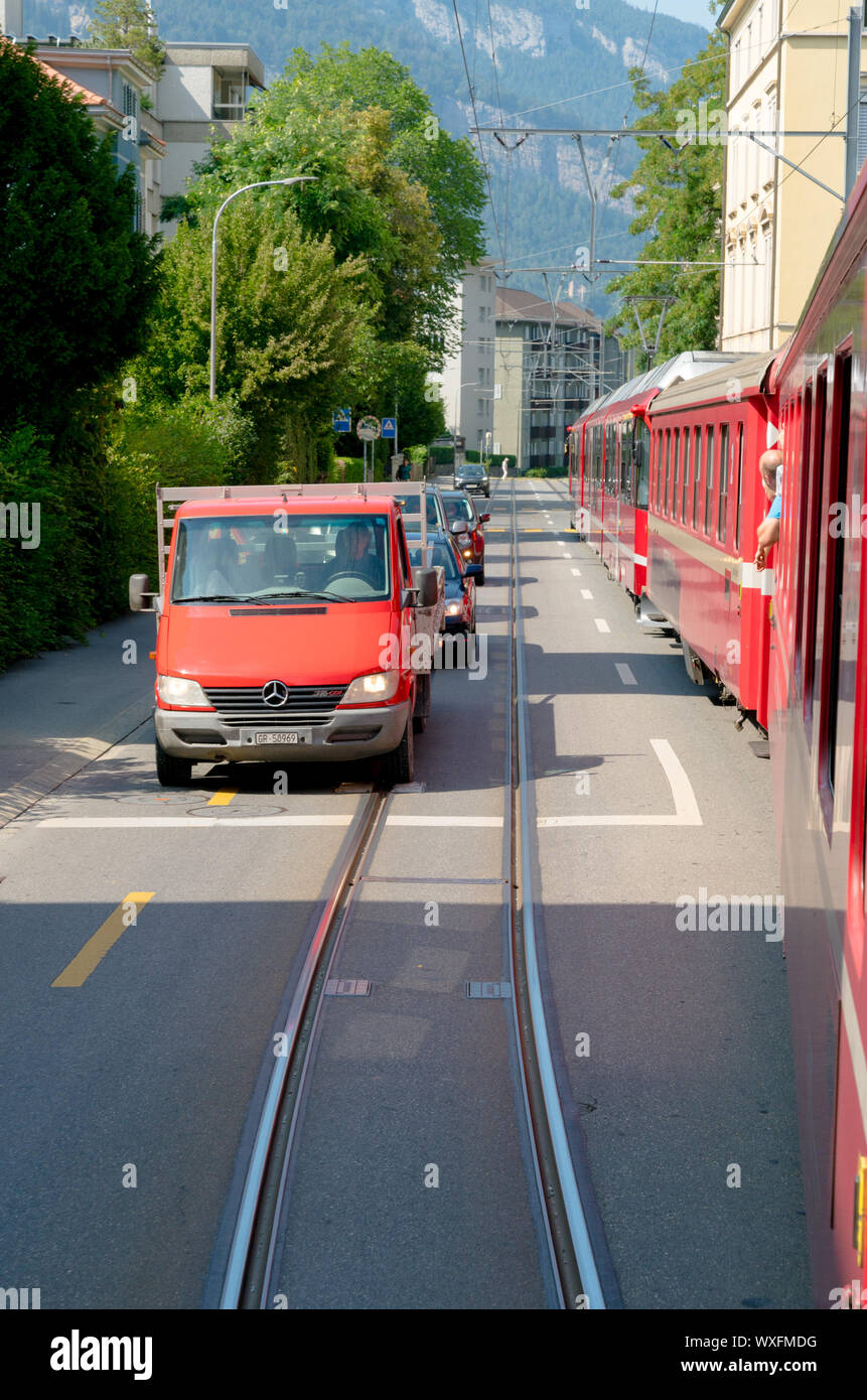 Red Rhatian Eisenbahn Zug stoppt Verkehr wie fährt er auf den Straßen der Innenstadt von Chur Stockfoto