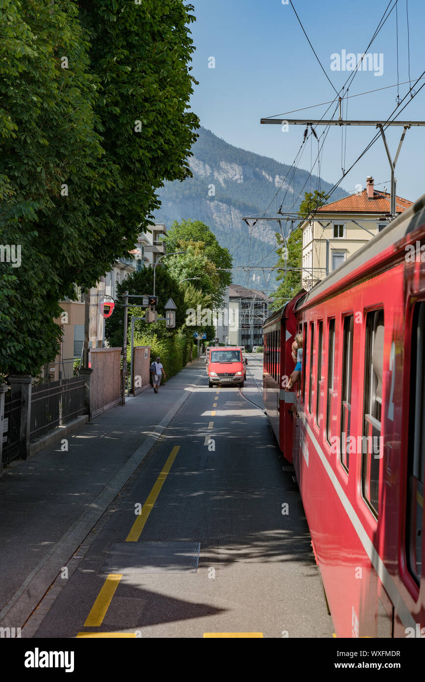 Red Rhatian Eisenbahn Zug stoppt Verkehr wie fährt er auf den Straßen der Innenstadt von Chur Stockfoto