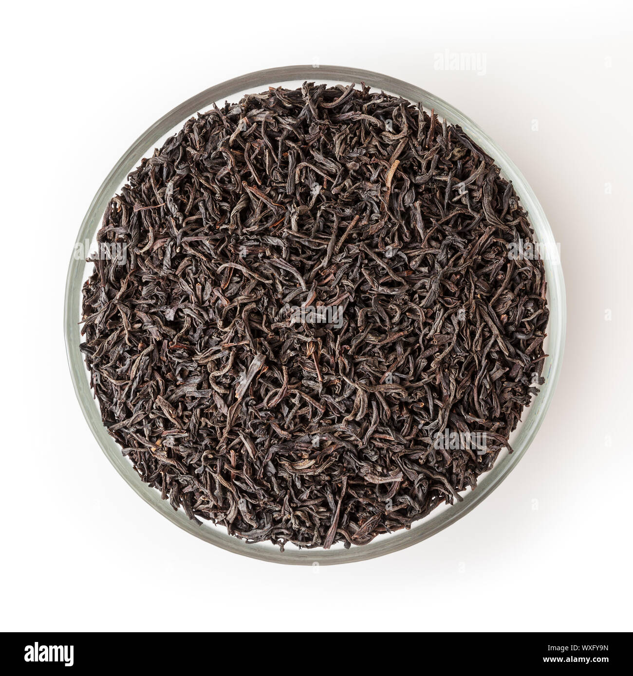Getrocknet schwarzer Tee in Glasschale auf weißem Hintergrund mit Freistellungspfad isoliert Stockfoto