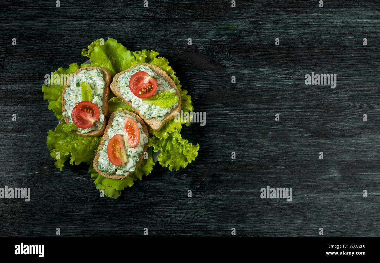 Sandwiches mit Gemüse. Frische Sandwiches mit Gemüse auf einem dunklen Board auf einen strukturierten Hintergrund. Blick von oben. Kopieren spa Stockfoto