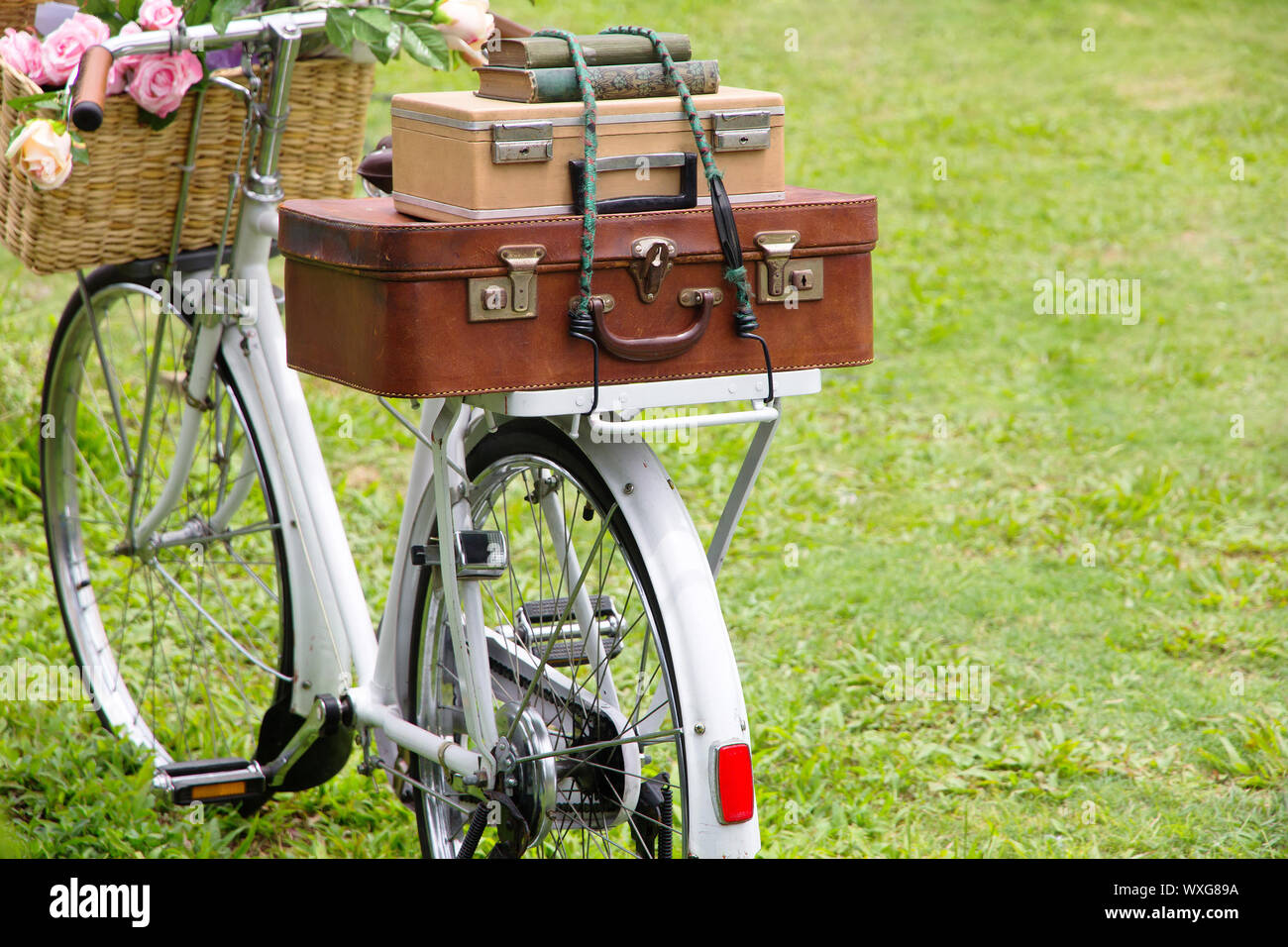 Oldtimer Fahrrad auf dem Feld mit einem Korb voller Blumen und Tasche Stockfoto