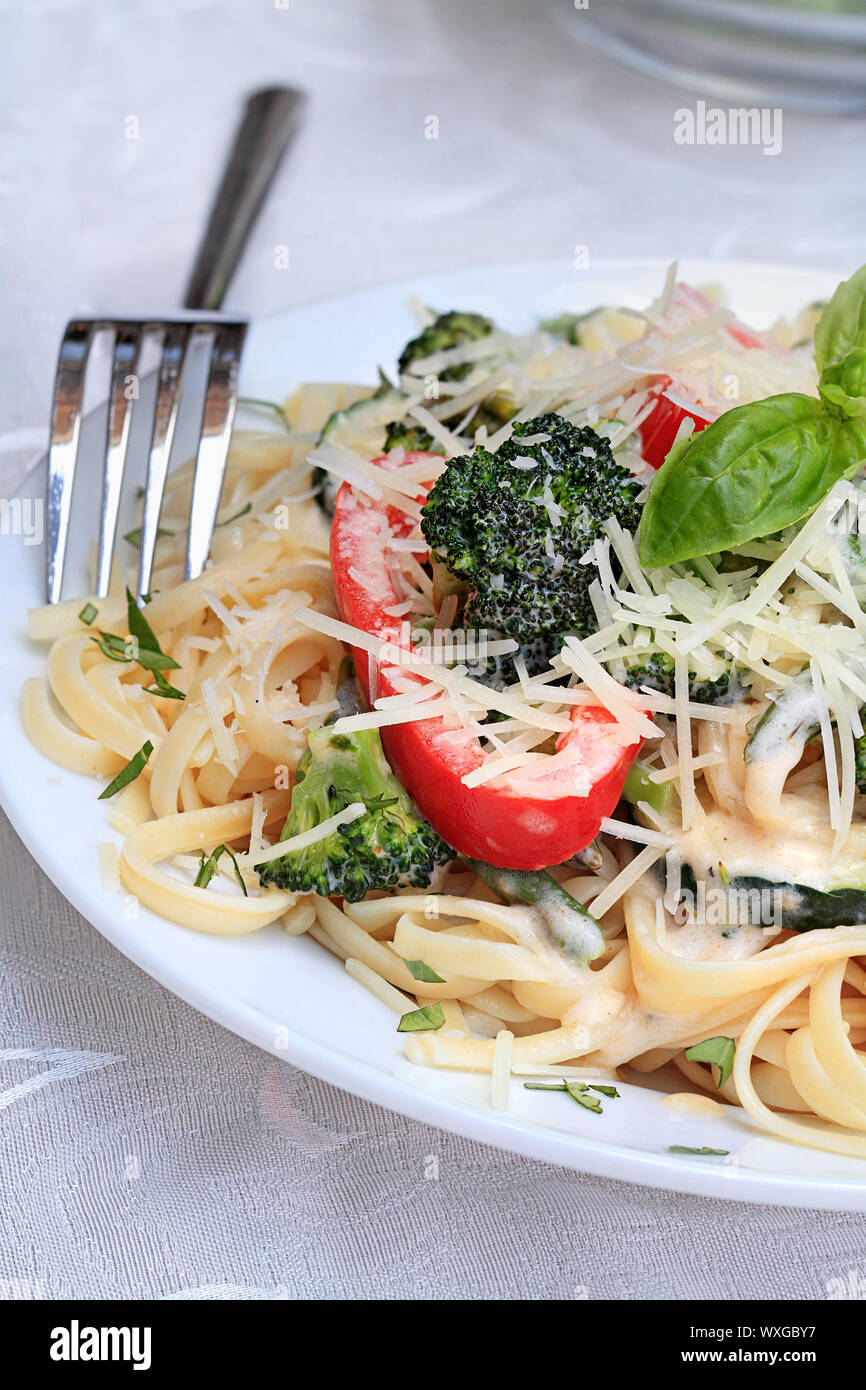 Pasta Primavera mit frischen Brokkoli, Spargel, rote Paprika und Zucchini mit frisch geriebenem Parmesan. Stockfoto