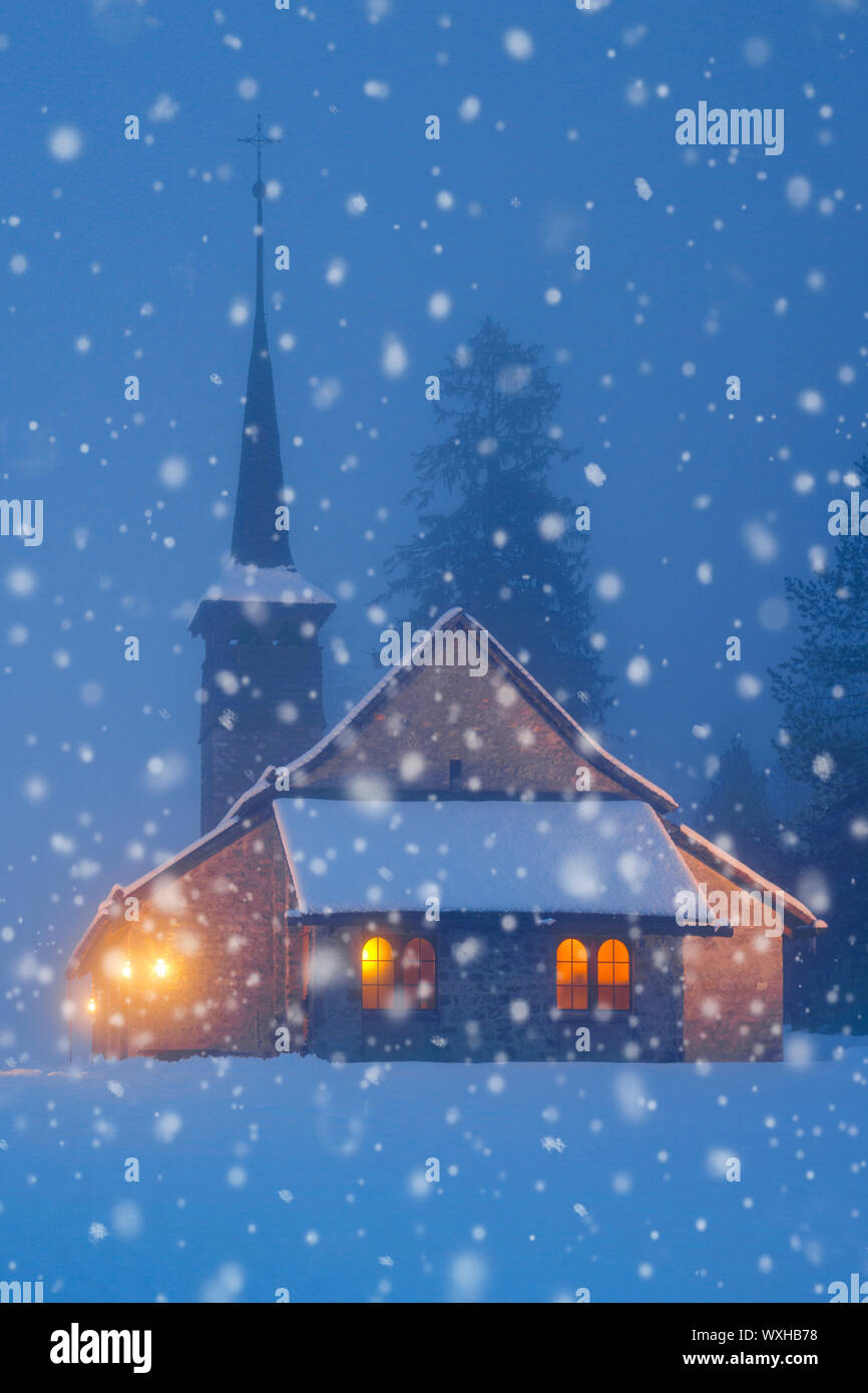 Beleuchtete Kapelle in der Schneefall in der Nacht. Kandersteg, Schweiz Stockfoto