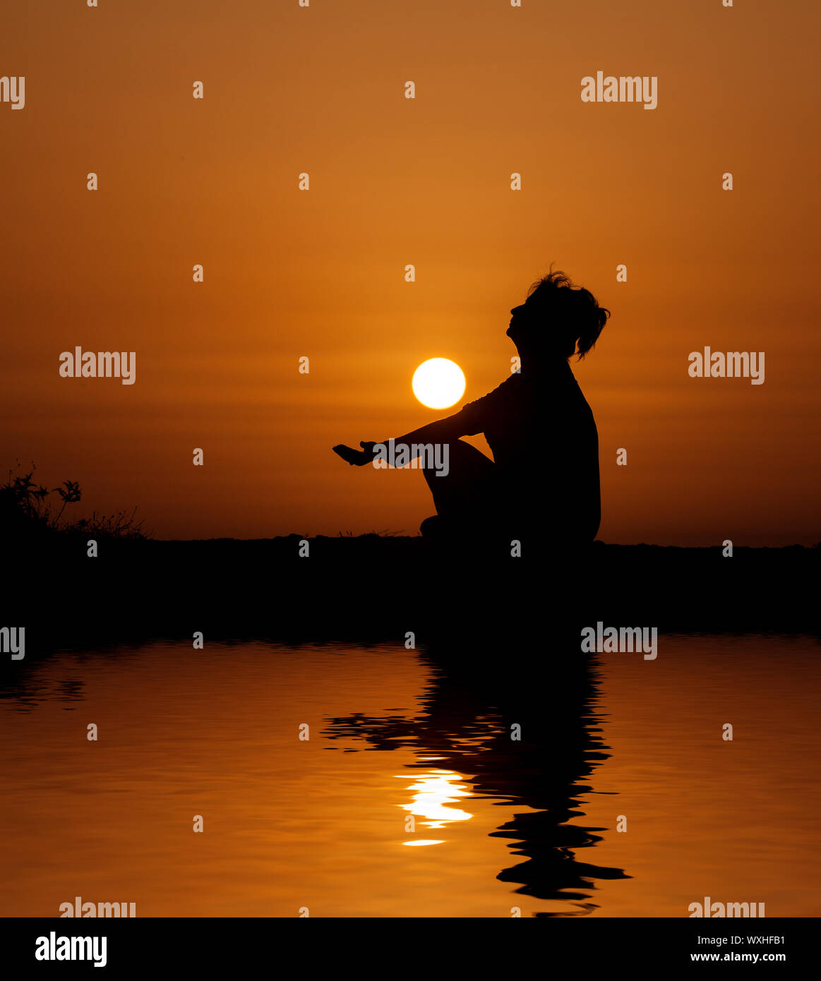 Silhouette Frau sitzen und entspannen gegen orange sunset Stockfoto