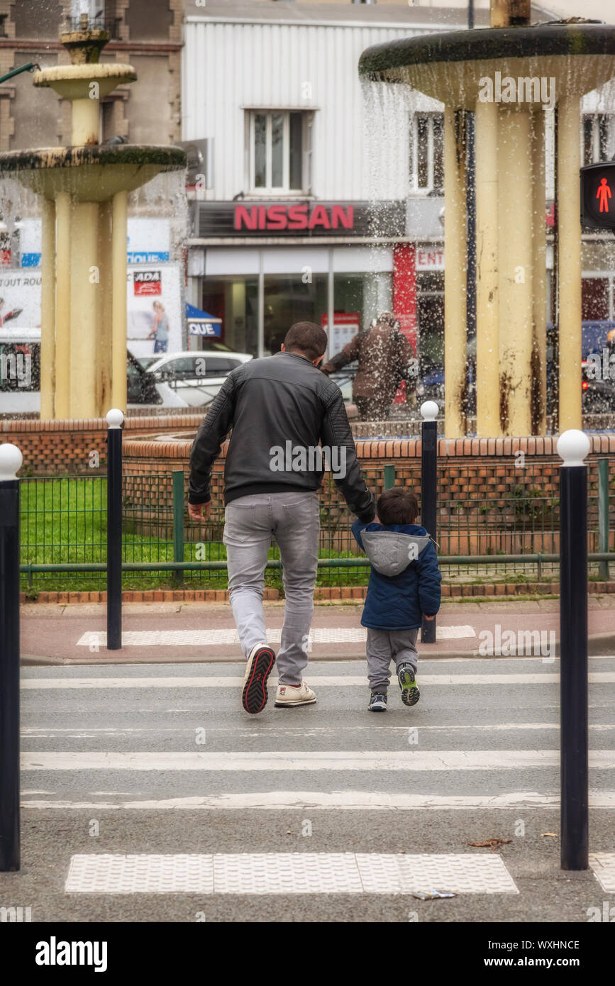 Die Straße überqueren, an der Hand ein Kind Stockfoto