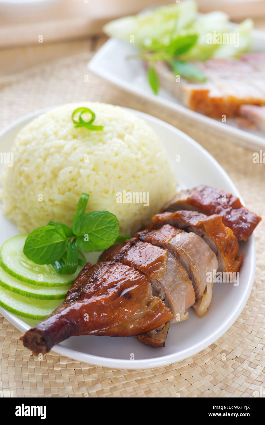 Gebratene Ente und knusprig gebratenes Schweinefleisch Siu Yuk, im chinesischen Stil, mit Reis auf Esstisch serviert. Singapur-Küche. Stockfoto