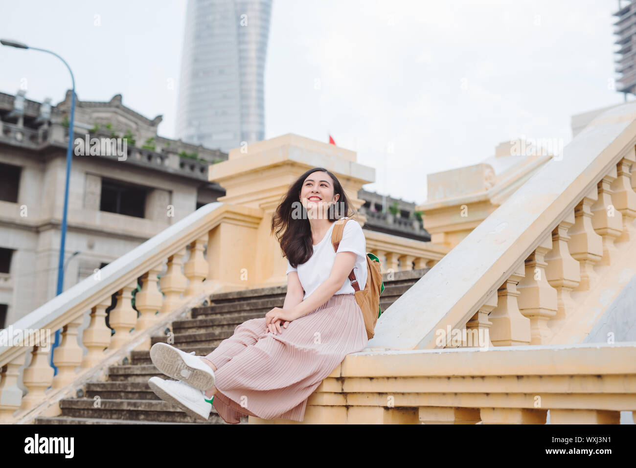 Lebensstil im Freien Nahaufnahme Portrait von glückliche junge Frau in stilvollen casual Outfit sitzt auf der Brücke auf der Straße. Ziemlich hipster Mädchen Spaß und Stockfoto