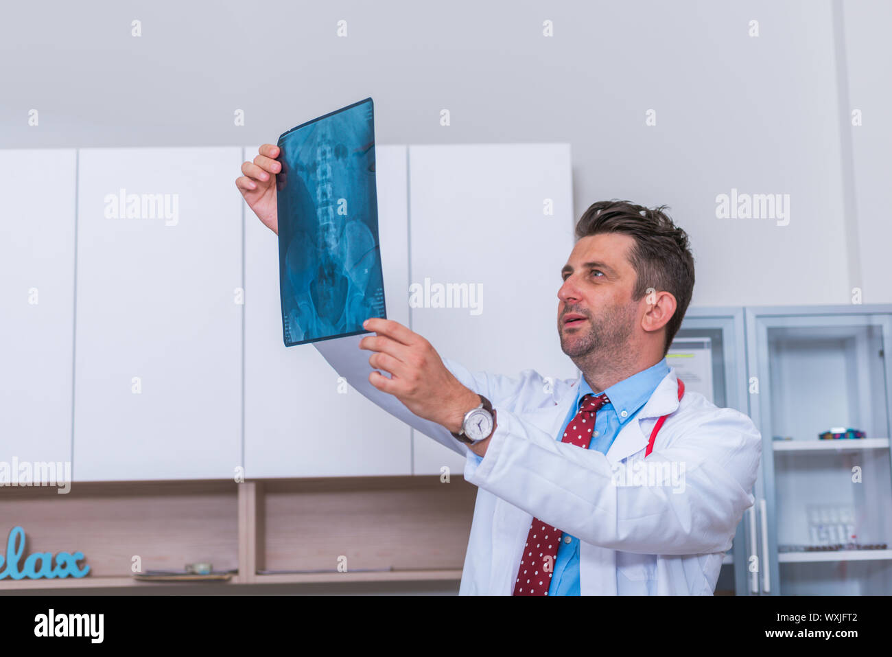 Männlicher Arzt in seiner Mitte 40 die Lesung ein Röntgenbild (Radiographie) von einem Patienten hip Region (COXA) beim Stehen in einem Krankenhaus Radiologie - Abteilung Stockfoto