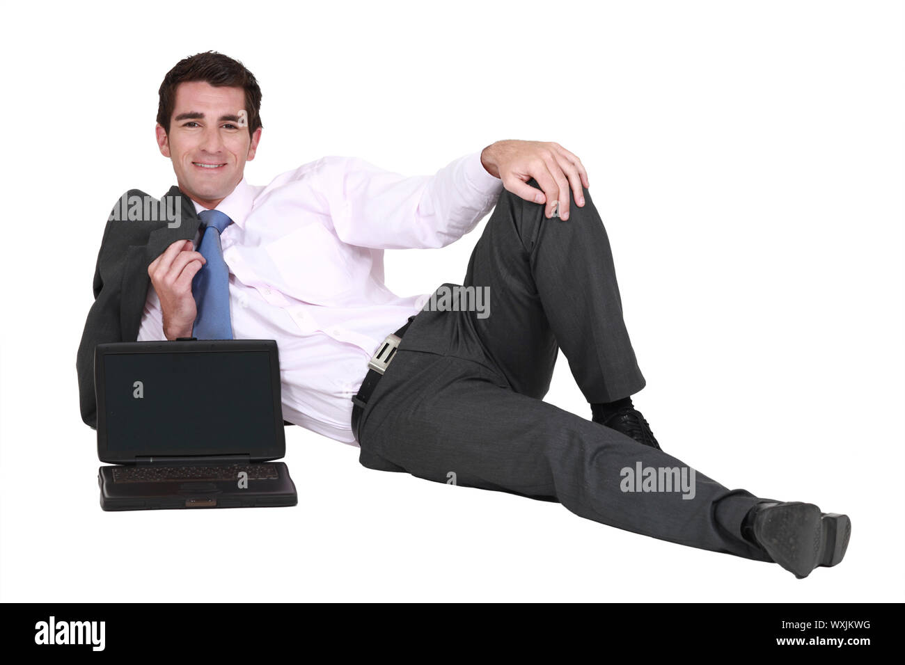 Geschäftsmann auf dem Boden liegend mit seinem Laptop Stockfoto