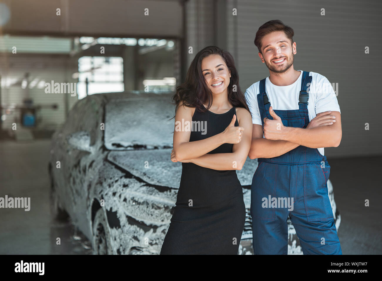 Jungen gutaussehenden Mann in Uniform und schöne Frau Client stehen in car wash Station angezeigt wie Zeichen. Stockfoto