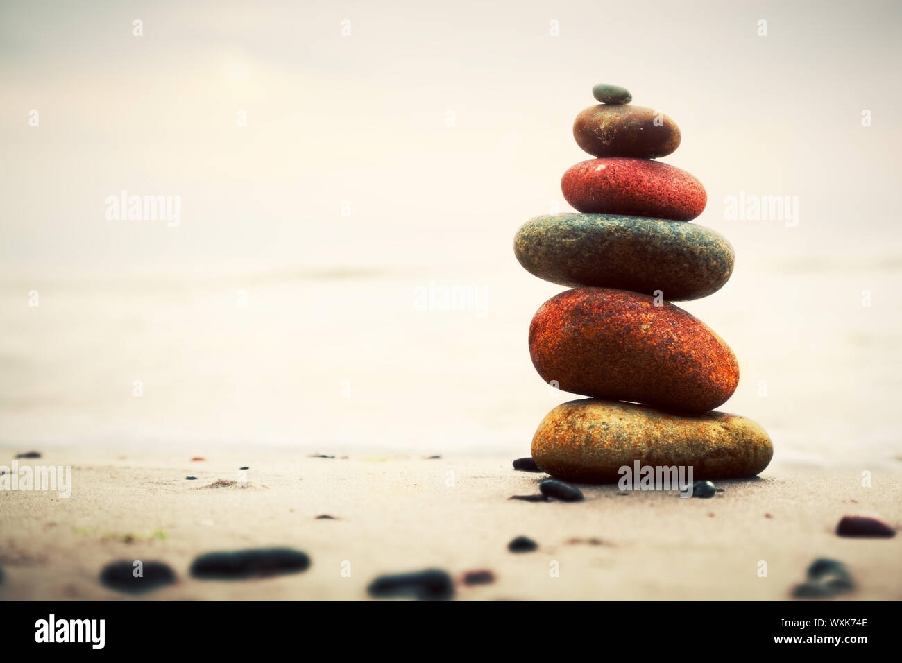 Steinen Pyramide auf Sand als Symbol für Zen, Harmonie und Balance. Ozean im Hintergrund Stockfoto