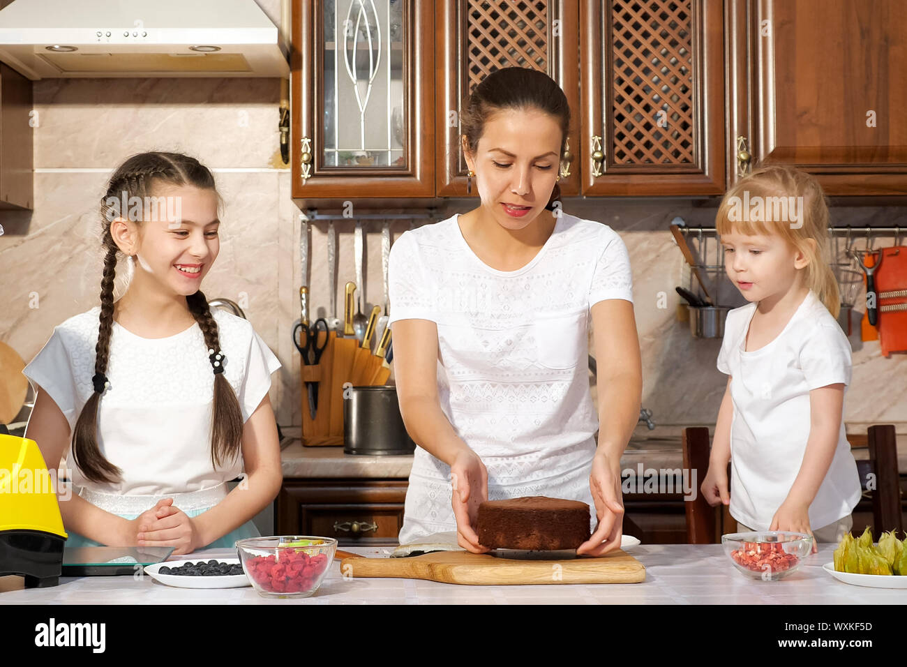 Junge Brunette Mutter Backt Kuchen Mit Ihren Beiden Kleinen Tochtern In Der Kuche Sie Zieht Den Kuchen Schwamm Aus Der Kuchenform Familie Kochen Stockfotografie Alamy