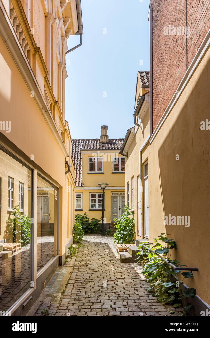 Eine enge Gasse mit Kopfsteinpflaster und gelben Gebäude auf jeder Seite, und der Himmel oben, Faaborg, Dänemark, 12. Juli 2019 Stockfoto