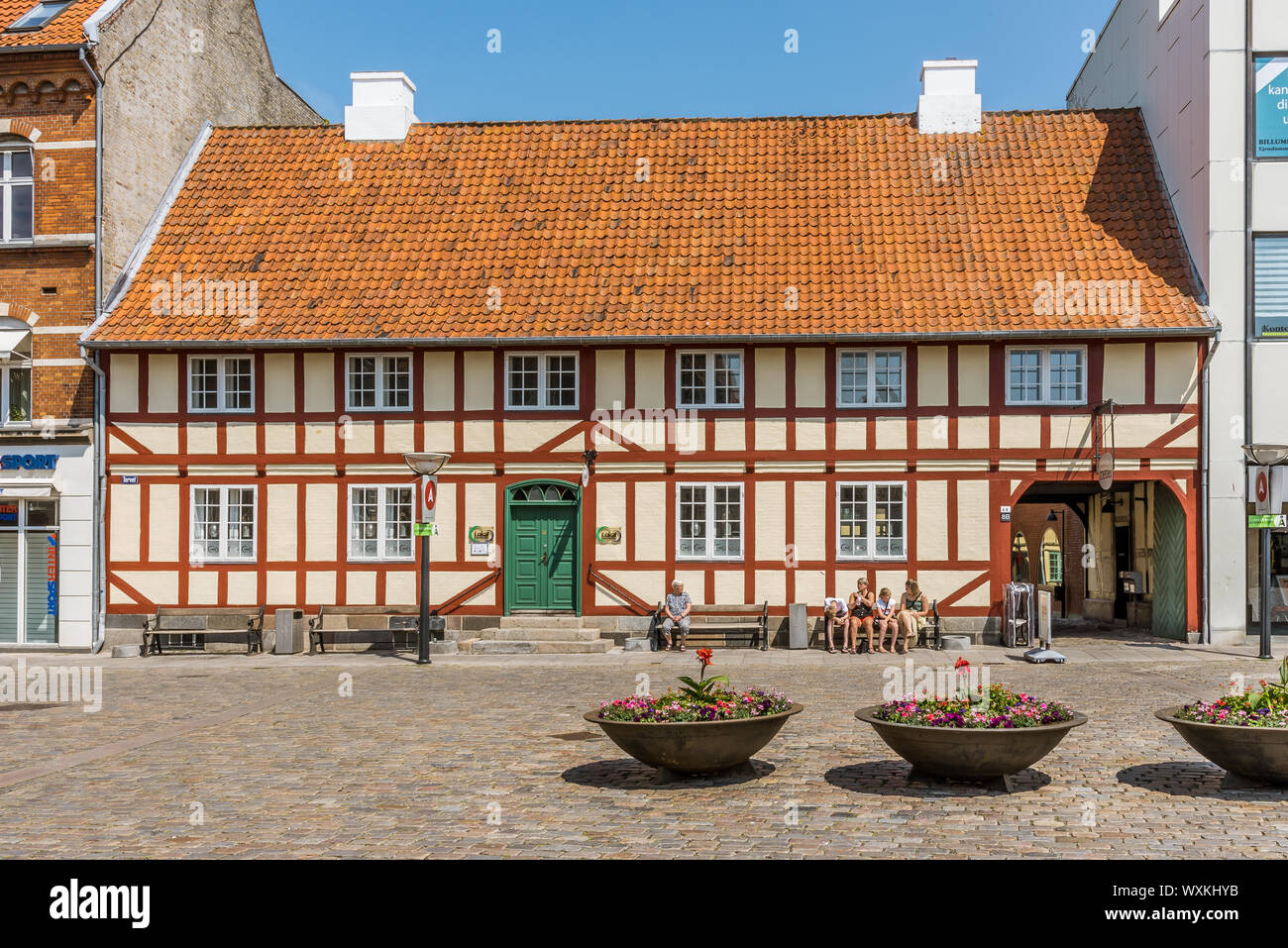 Menschen sitzen in der Sonne vor einem riesigen Fachwerkhaus in Faaborg, Dänemark, 12. Juli 2019 Stockfoto