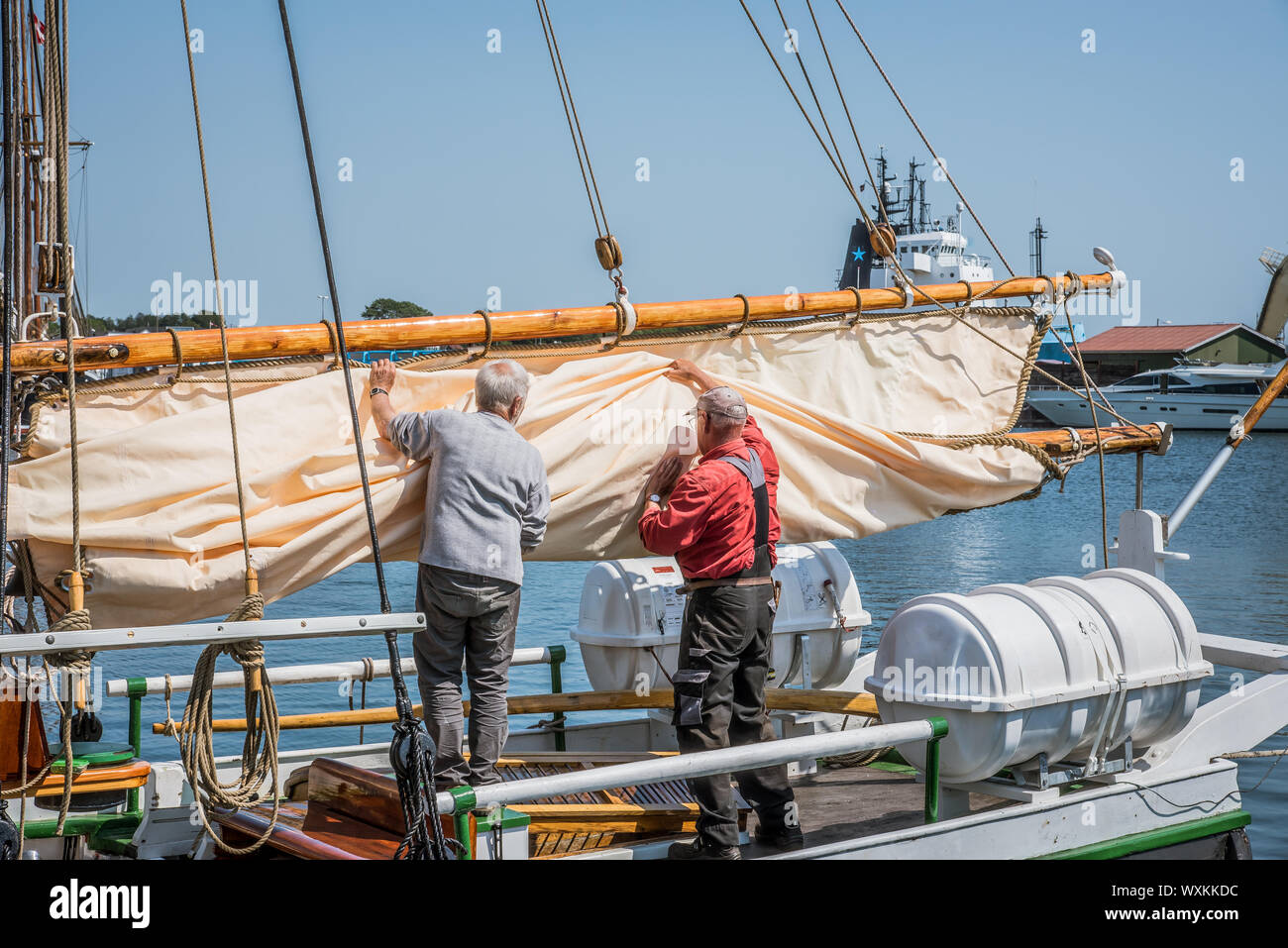 Zwei fischer Vorbereitung der Segel eines alten fishingboat im Quay in Faaborg, Dänemark, 12. Juli 2019 Stockfoto