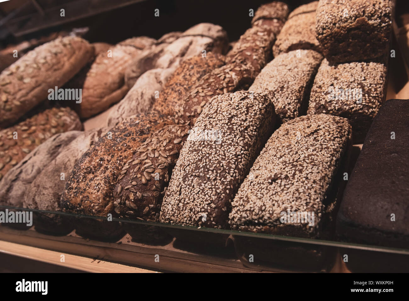 Viele verschiedene gesunde Brot mit mit Sonnenblumenkerne und Sesam auf einem Brot Regal in einem Lebensmittelgeschäft. Roggen frische Backwaren. Stockfoto