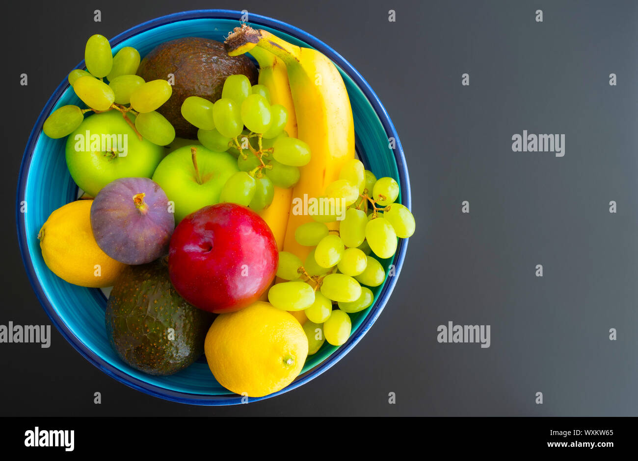 Blick von oben auf die Keramik Schüssel mit frischem Bio-Obst auf dunklem Hintergrund gefüllt Stockfoto