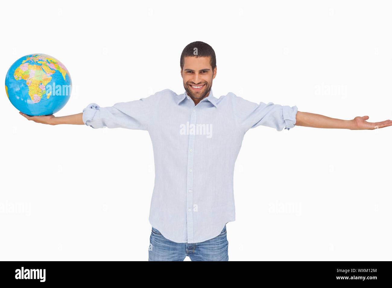 Lächelnder Mann hält einen Globus und anderen Arm ausgestreckt auf weißem Hintergrund Stockfoto