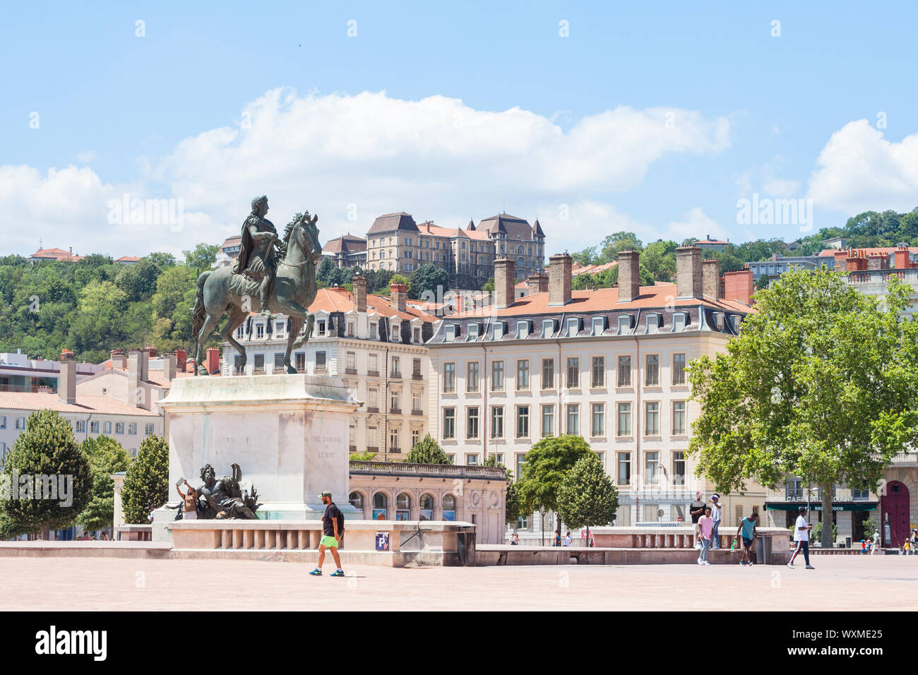 LYON, Frankreich - 14 Juli, 2019: Roi Louis XIV Statue auf den Place Bellecour Square, in der Innenstadt von Lyon, mit Fußgängern vorbei. Es ist der Hauptplatz Stockfoto