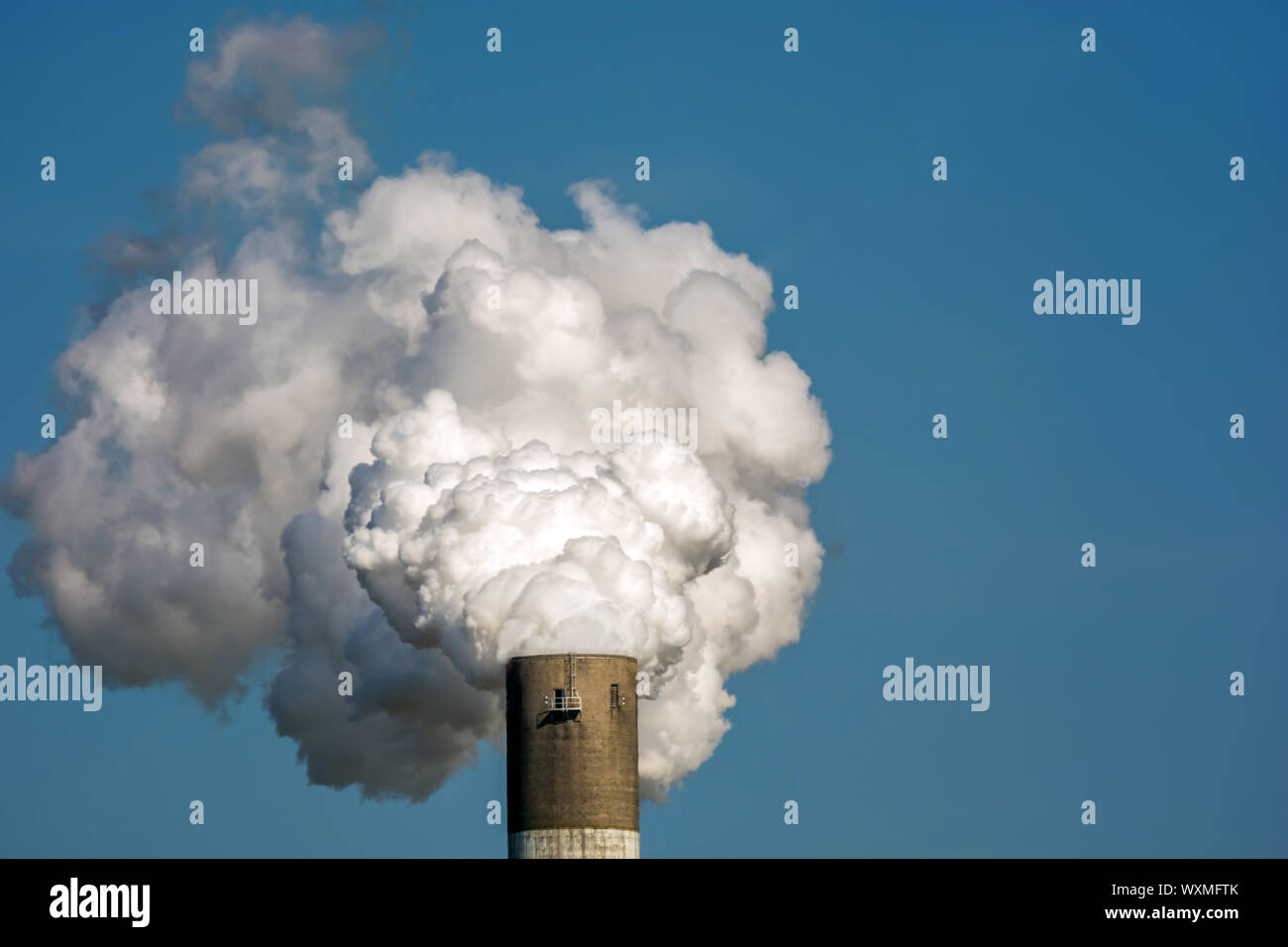 Abgase und Schadstoffe, die durch die Industrie am Beispiel einer rauchenden Schornstein Stockfoto