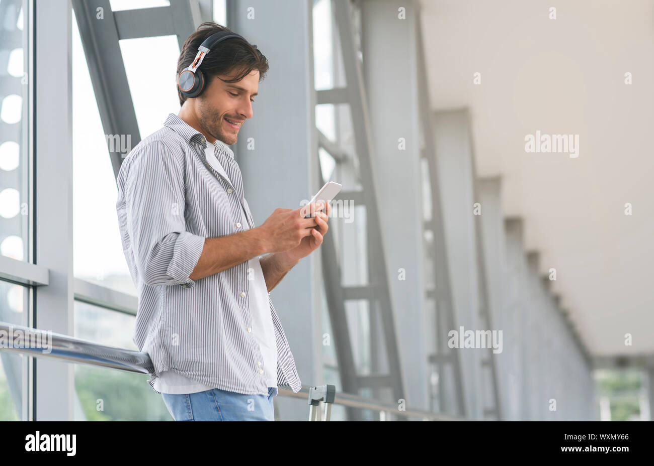 Junger Mann in Kopfhörer auswählen Titel auf dem Smartphone Stockfoto