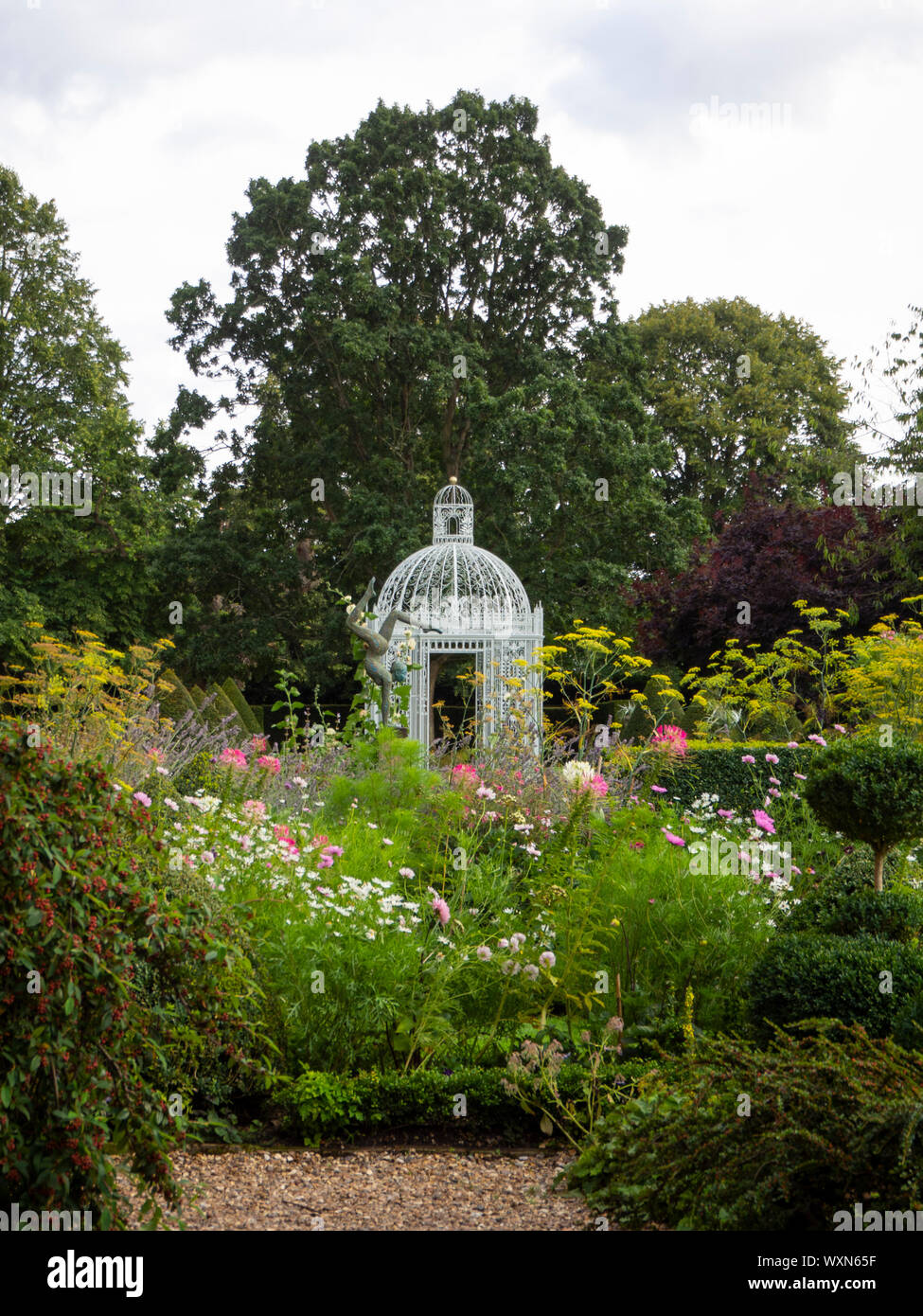 Chenies Manor Garden mit Blick auf die weissen Vogelkäfig Pagode im Parterre in der treescape; eine Skulptur erhebt sich über Kosmos, cleome und Fenchel. Stockfoto