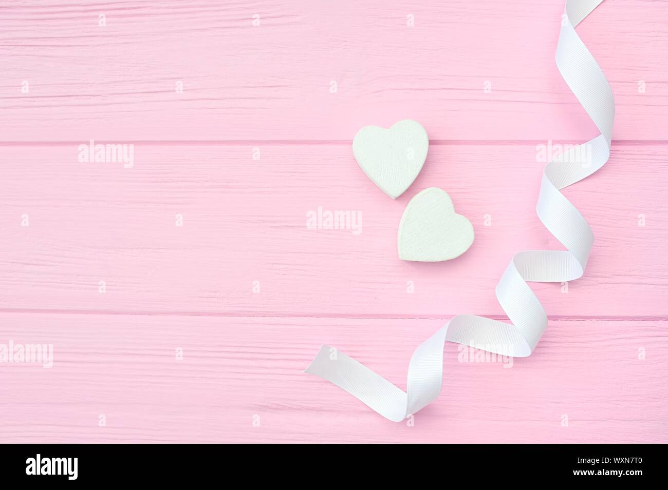 Zwei weißen Herzen und Farbband auf rosa Hintergrund aus Holz mit Platz für deine Liebe Text. Flach, Ansicht von oben. Valentines Tag design Stockfoto