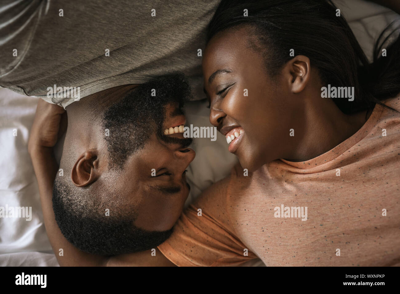 Liebevolle junge afrikanische amerikanische Paar zusammen im Bett lachen Stockfoto