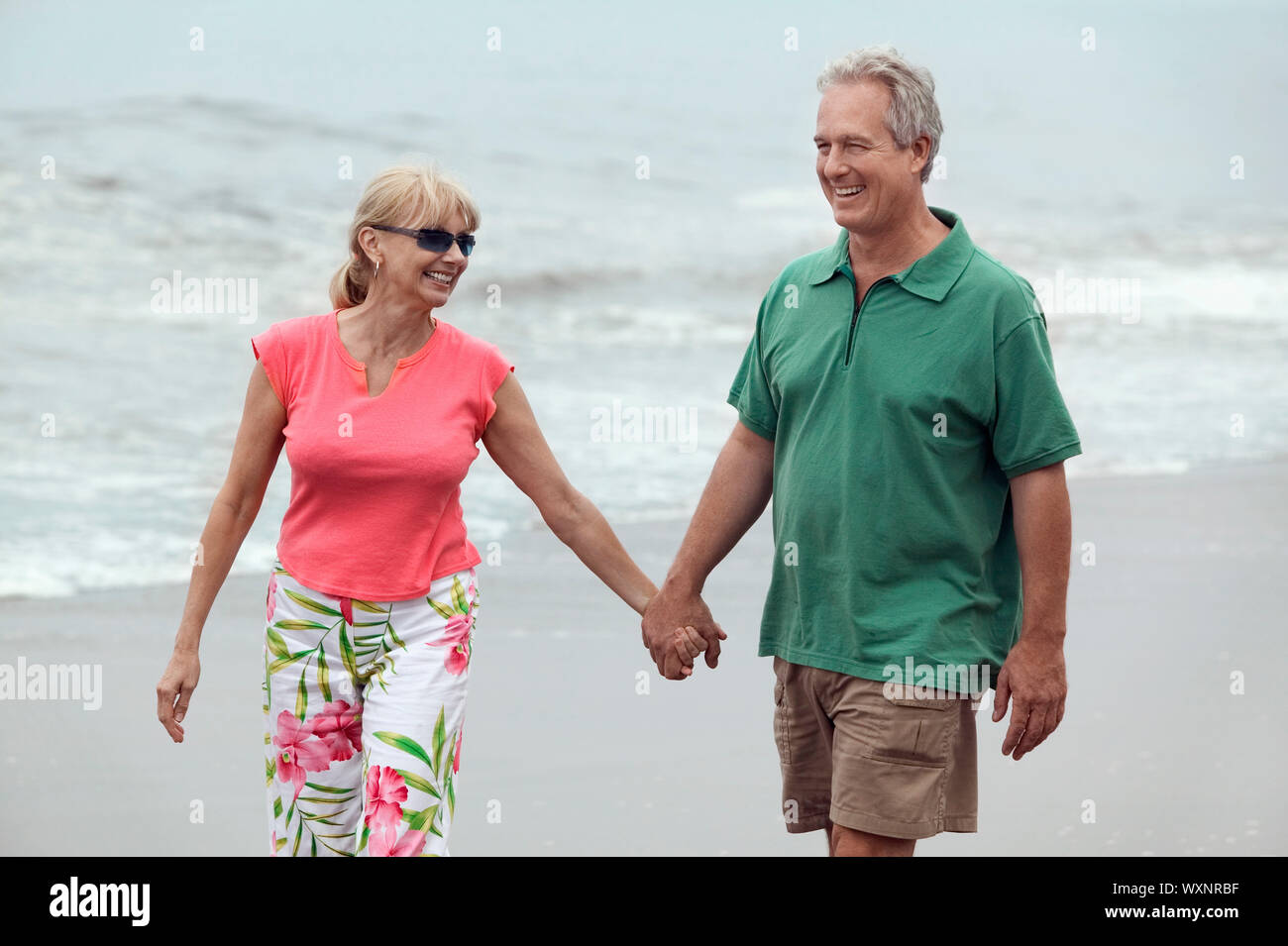 Paare, die Hand in Hand am Strand Stockfoto