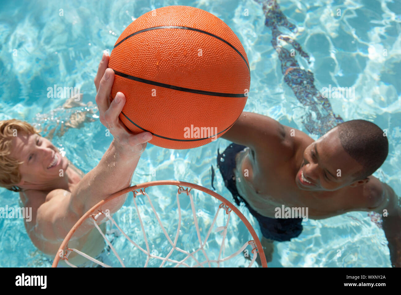 Zwei junge Männer, Wasserbasketball spielen Stockfoto