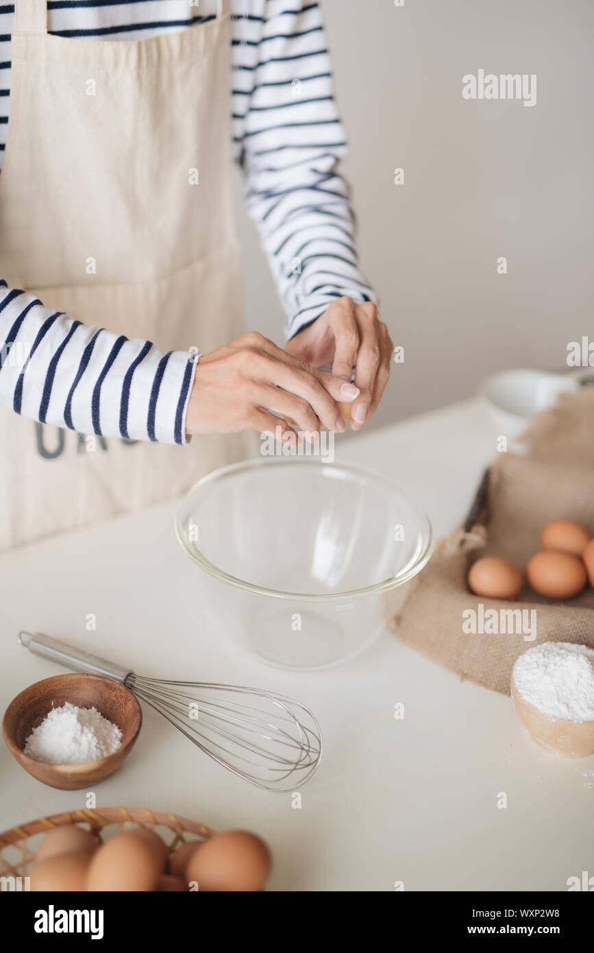 Horizontale schoss der schweren männlichen tragen beige Schürze brechen Ei in Metallschale Stockfoto