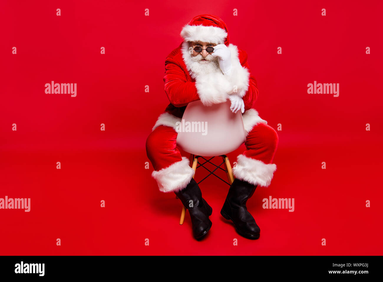 Winter Dezember noel Konzept. Volle Beine Körper Größe stilvolle Sankt  Nikolaus in Schuhe Kopfbedeckung Handschuhe mit weißen Bart auf Stuhl Blick  an Kamera Stockfotografie - Alamy