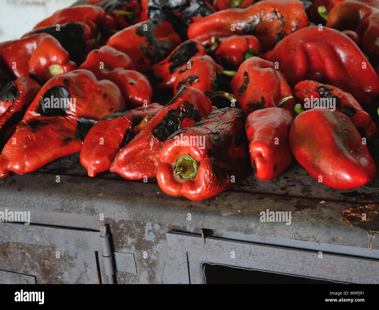 Geröstete Paprika auf alten schwarz Holz Herd kochen. Gebackene süsse rote Paprika Stockfoto
