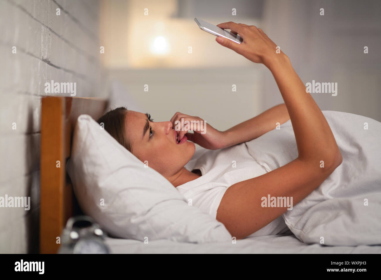 Angst Mädchen, dass Smartphone Liegen im Bett zu Hause. Stockfoto