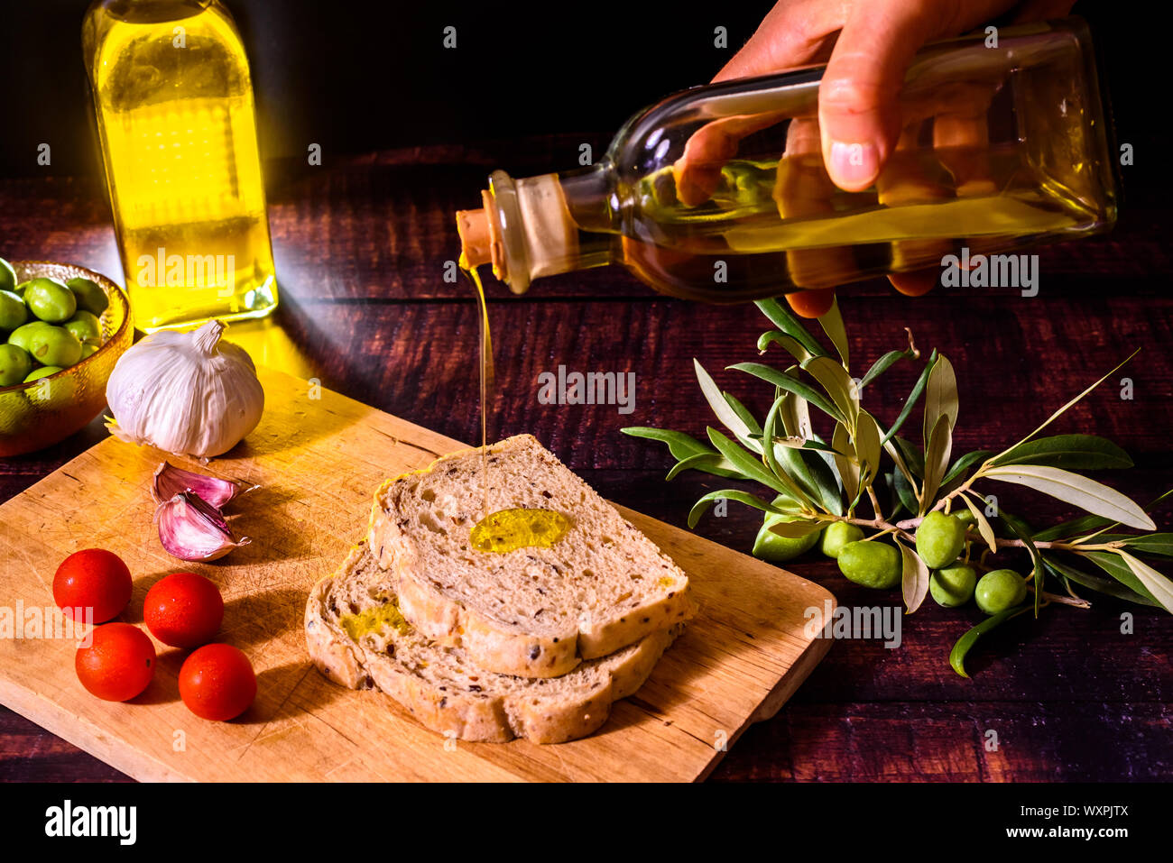 Ein mediterranes Kochen bereitet eine Scheibe Brot mit Olivenöl, Tomaten und Knoblauch, einem traditionellen Frühstück im mediterranen Ländern. Stockfoto