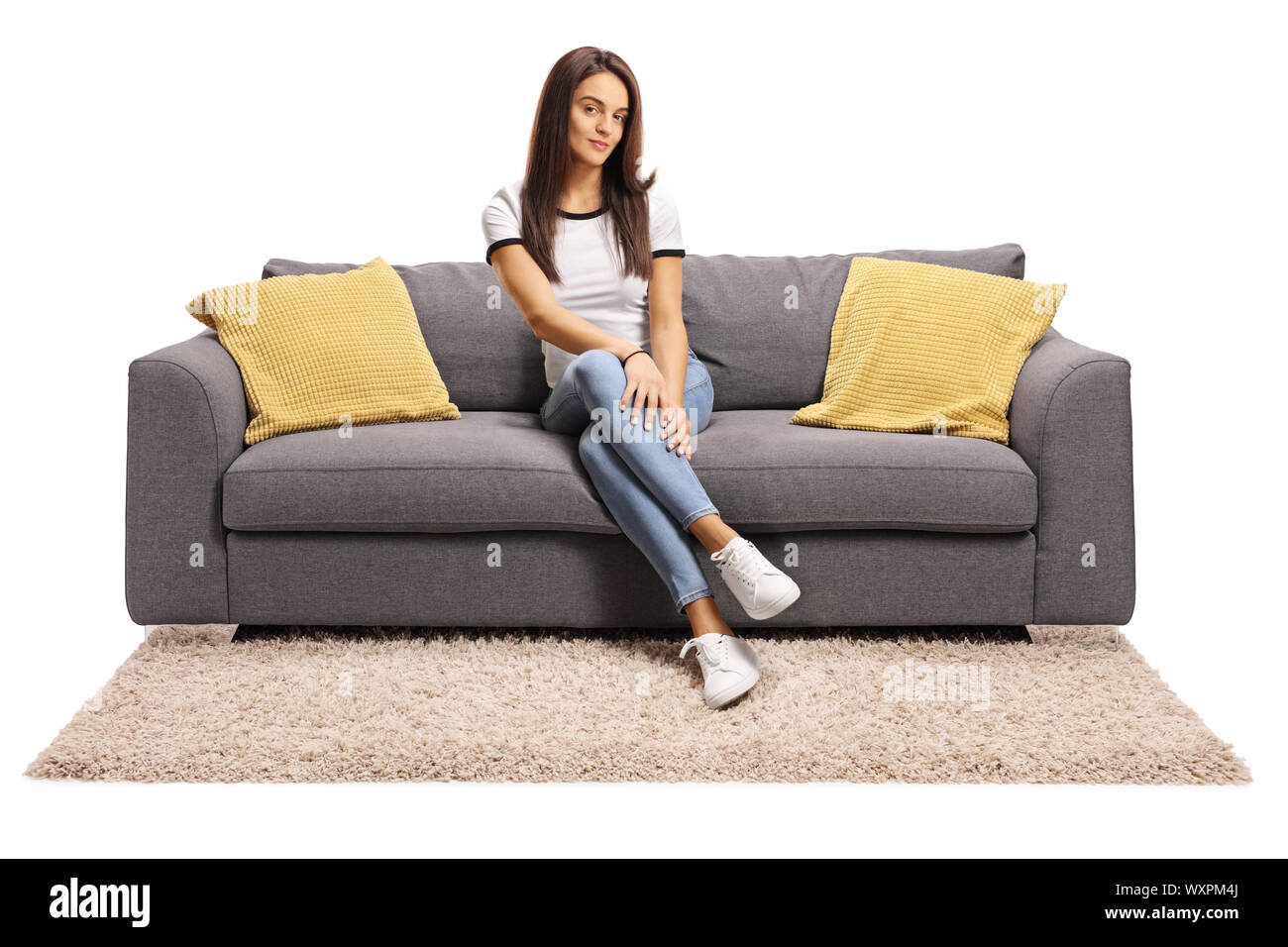 In voller Länge Porträt einer jungen Frau auf der Couch sitzen mit gekreuzten Beinen auf weißem Hintergrund isoliert Stockfoto