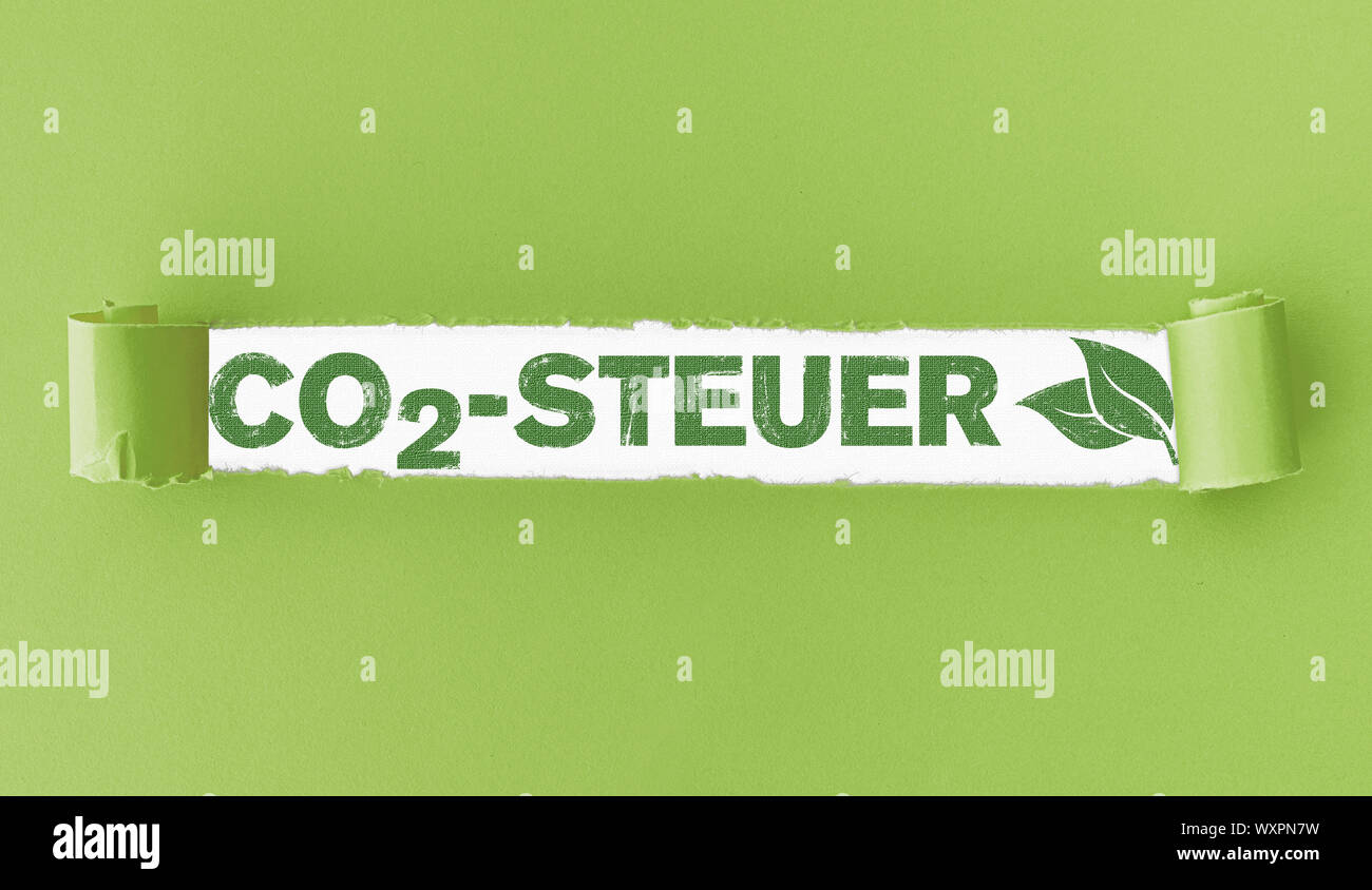 Zerrissenes Papier mit Text CO2-Steuer, Deutsch für CO2-Steuer, und grüne Blätter in der Öffnung Stockfoto
