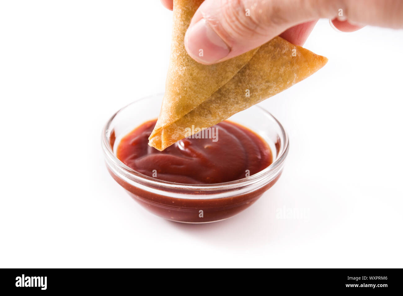 Hand mit samosa Eintauchen in süß-saurer Soße auf weißem Hintergrund. Traditionelle indische Küche Stockfoto