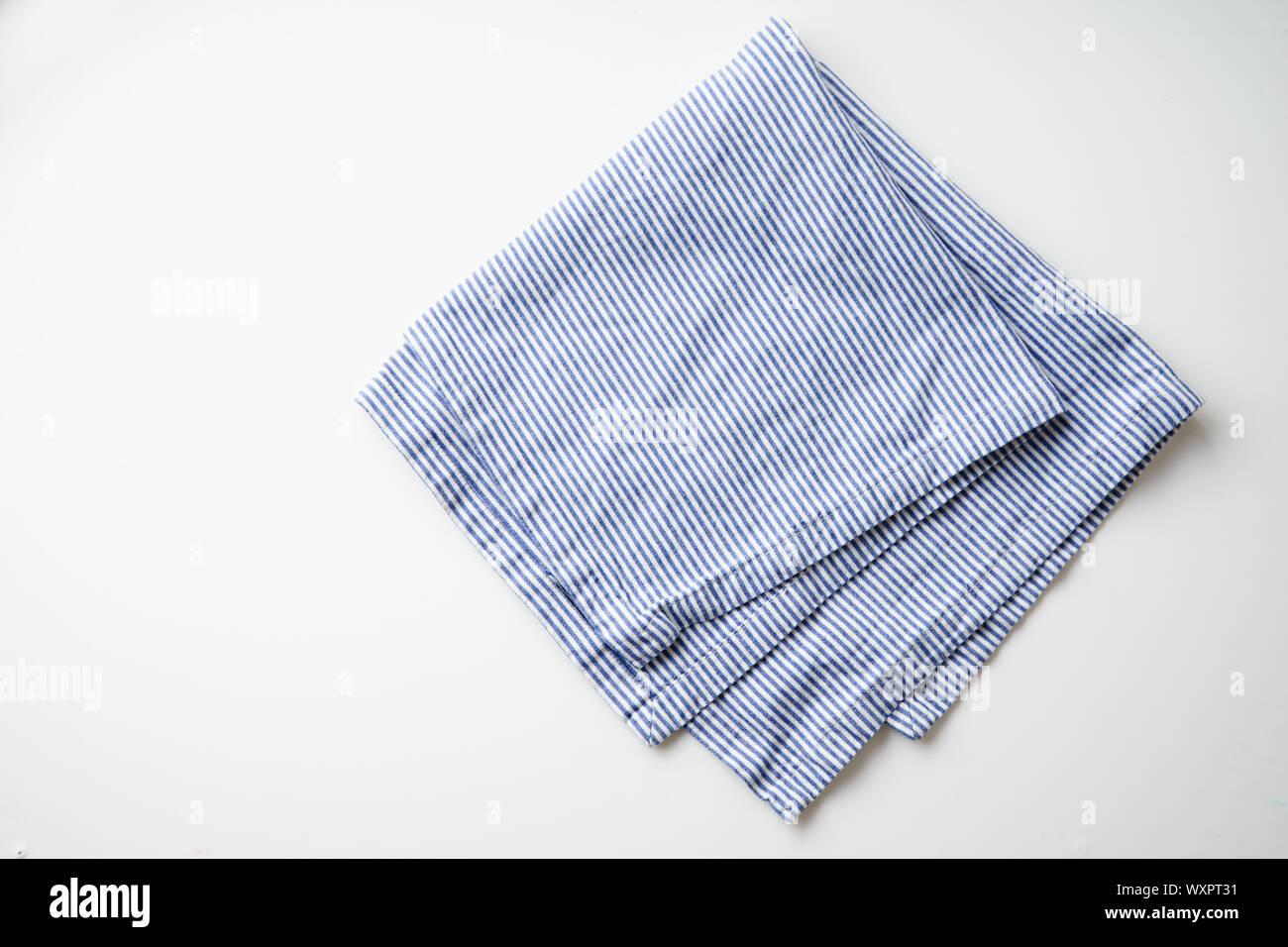 Blau und Weiß textil Serviette auf weißem Hintergrund gefaltet gestreift. Foodstyling element Stockfoto