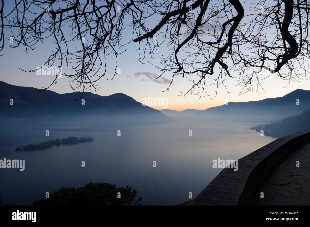 Alpine Lake in der Dämmerung mit Insel und Berg im Tessin, Schweiz. Stockfoto