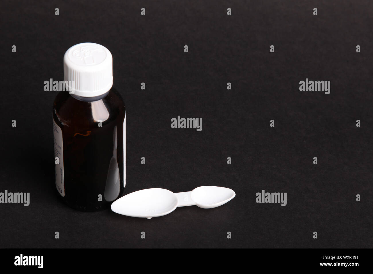 Medizinische Dosierung Löffel mit Medizin Flasche zum oralen Gebrauch auf schwarzen Hintergrund mit Kopie Raum Stockfoto