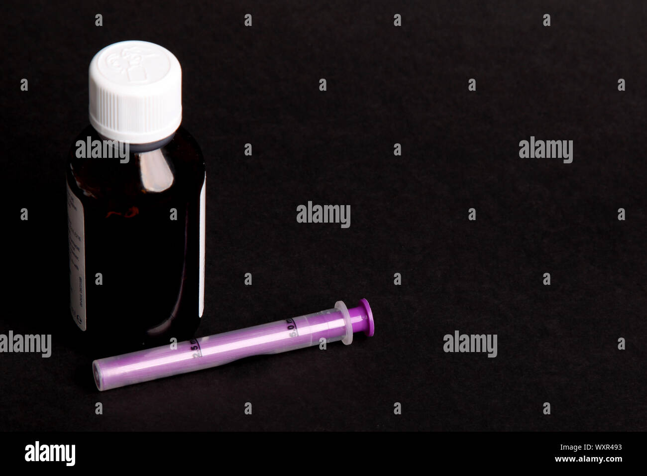 Medizinische Dosierung Spritze mit Medizin Flasche zum oralen Gebrauch auf schwarzen Hintergrund mit Kopie Raum Stockfoto
