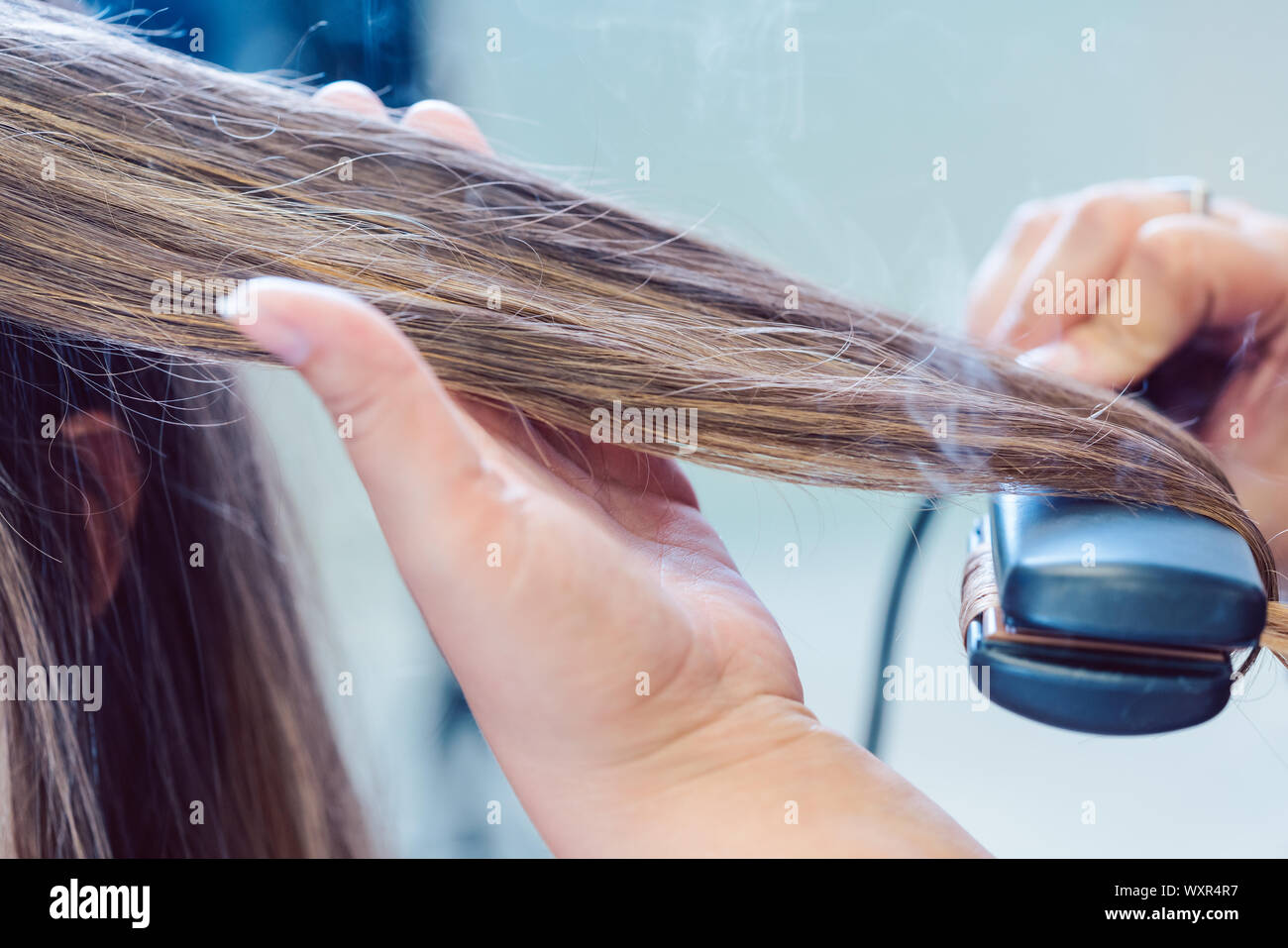 Friseur mit Bügeleisen auf das Haar der Frau Kunde, closeup Schuß Stockfoto