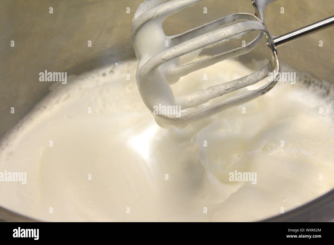 Geschlagener Eischnee und Zucker, Edelstahl Topf zum Backen cream Topping - eine moderne Küche Mixer verwendet das Eiweiß zu schlagen. Stockfoto