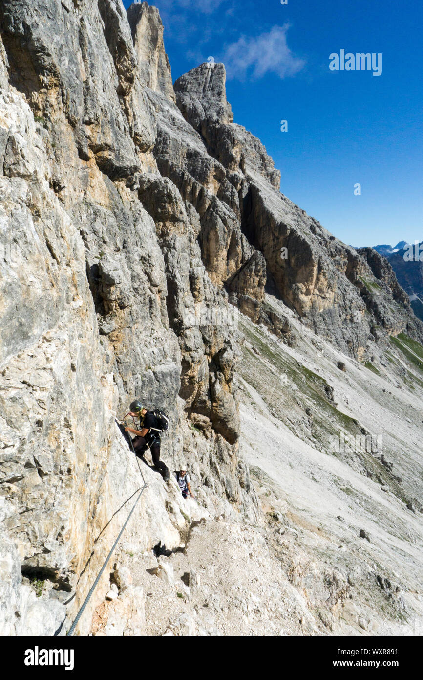 Attraktive Blondine weiblichen Bergsteiger auf einem steilen Klettersteig über Cortina d'Ampezzo Stockfoto