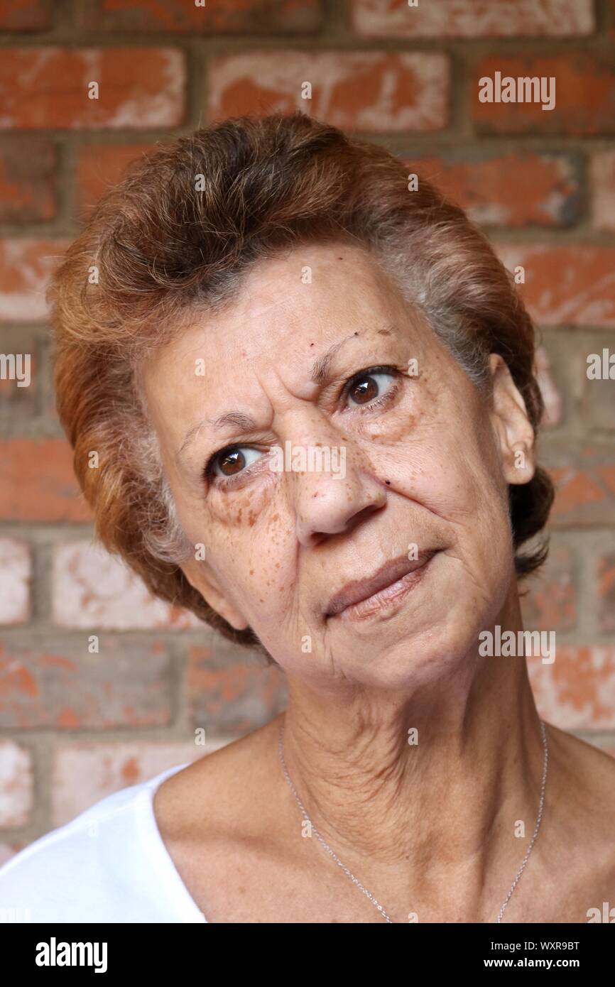 Porträt einer älteren Frau, die den Kopf gekippt und eine nachdenkliche Stare Stockfoto