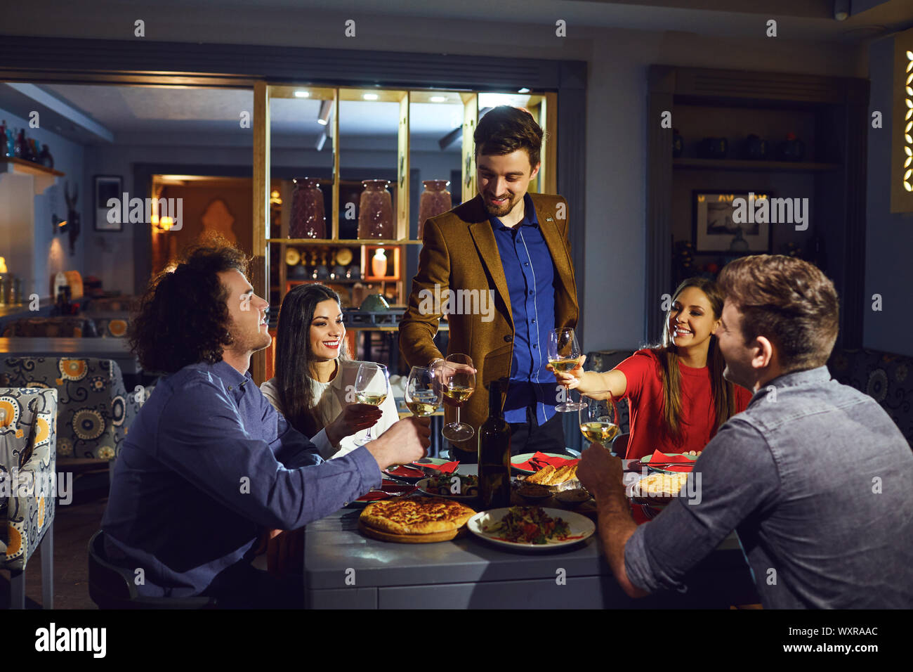 Freunde gratulieren einem Freund bei einem Abendessen in einem Restaurant. Stockfoto