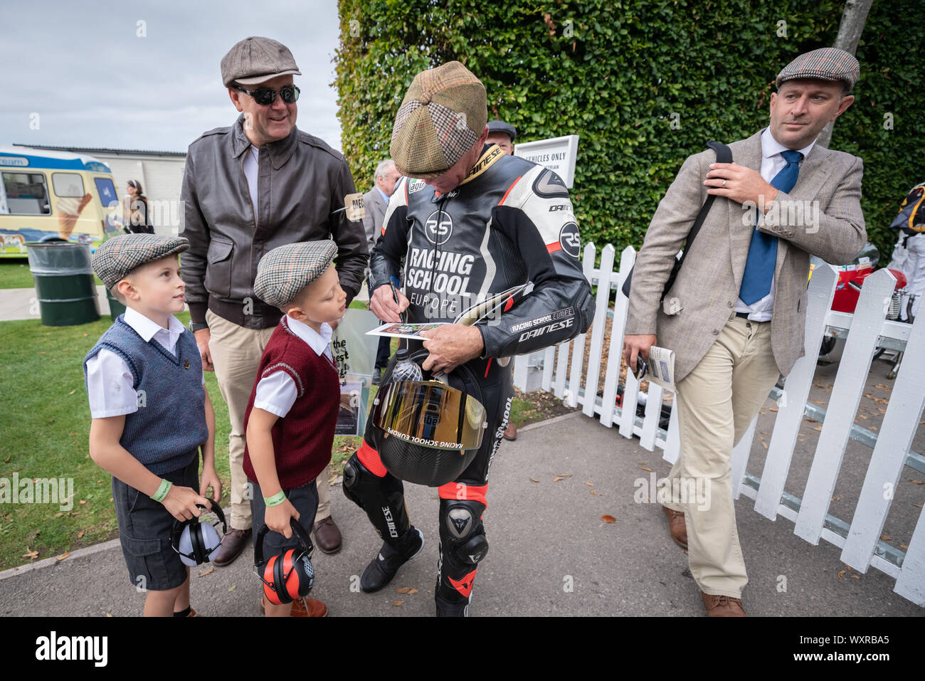 Troy Corser, Australische ehemalige Motorrad road racer, gibt Autogramme junge Fans während der weinlese-themed Goodwood Revival Festival. Stockfoto