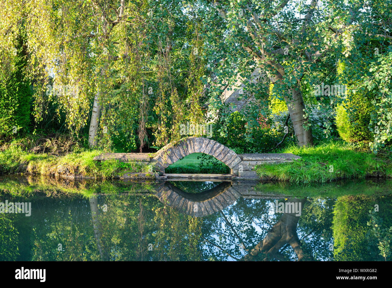 Kleiner Stein garten Brücke über den Fluss Windrush am frühen Morgen die Sonne. Bourton auf dem Wasser, Cotswolds, Gloucestershire, England Stockfoto