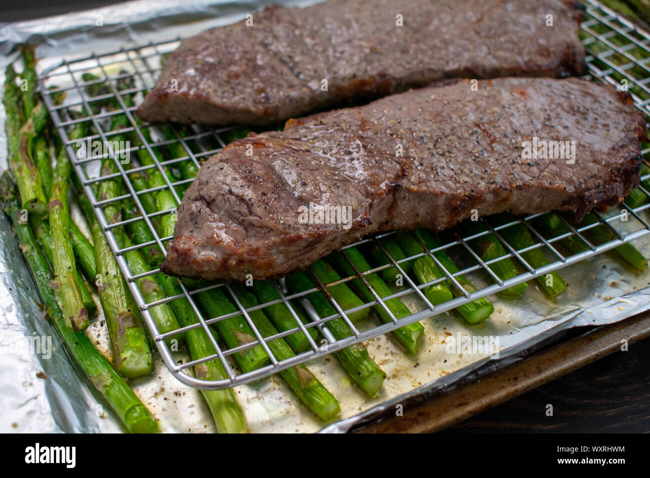 Rindfleisch und Spargel gebraten auf einem Blatt Pan: Sirloin Steak gebraten auf einer Folie ausgekleideten Blatt pan mit Spargelspitzen. Stockfoto